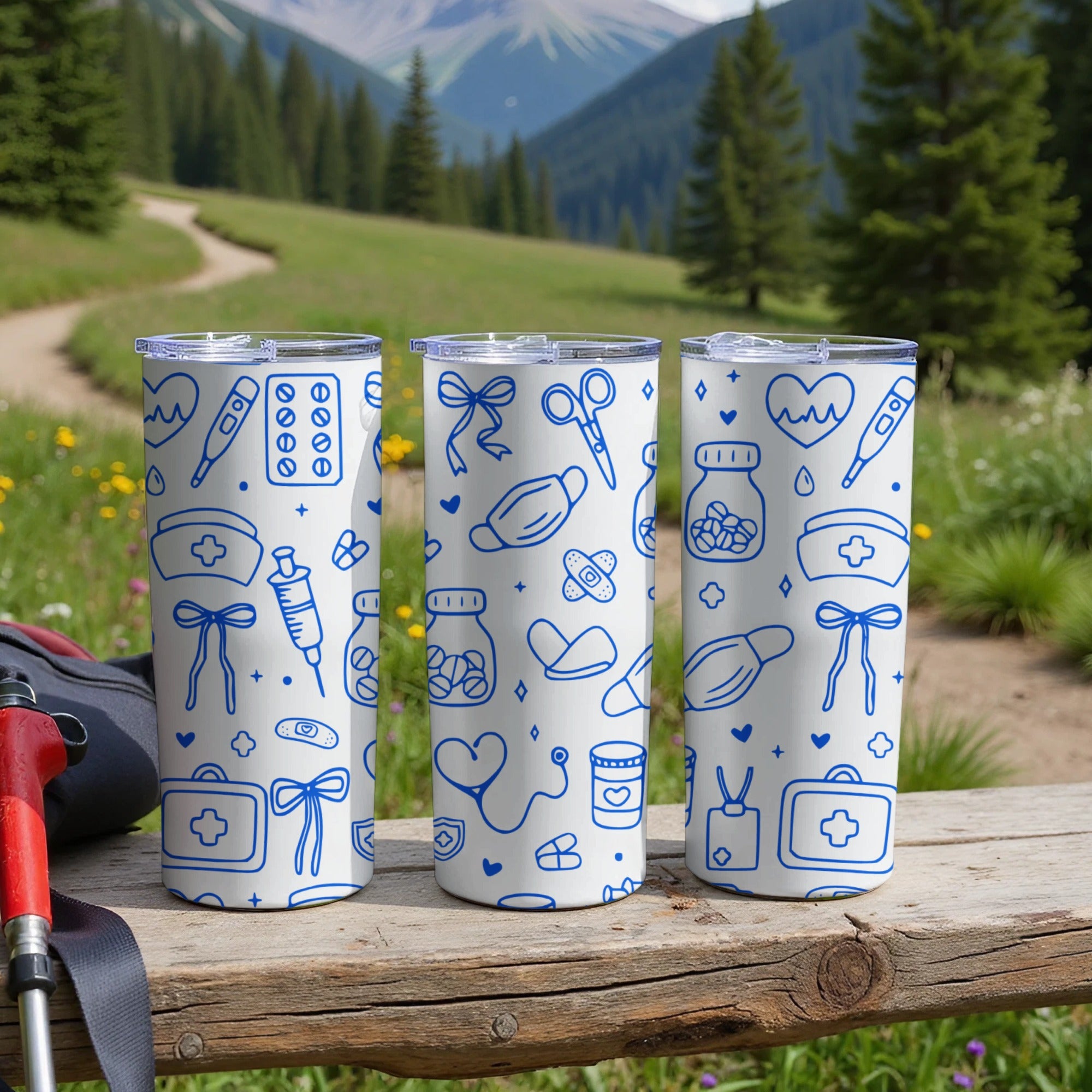 Three white tumblers with medical icons on a wooden surface outdoors.