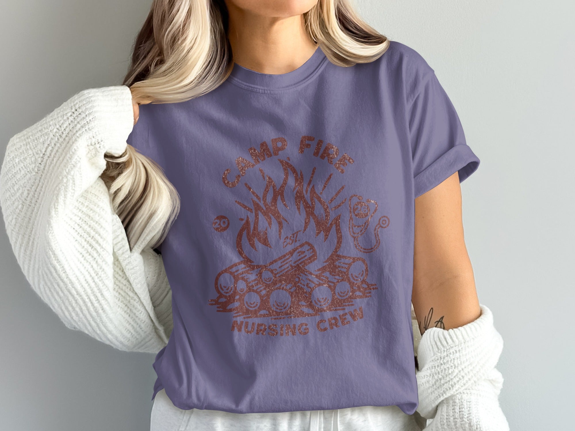 Camp Fire Nursing Crew design with flames and woodpile on purple t-shirt.