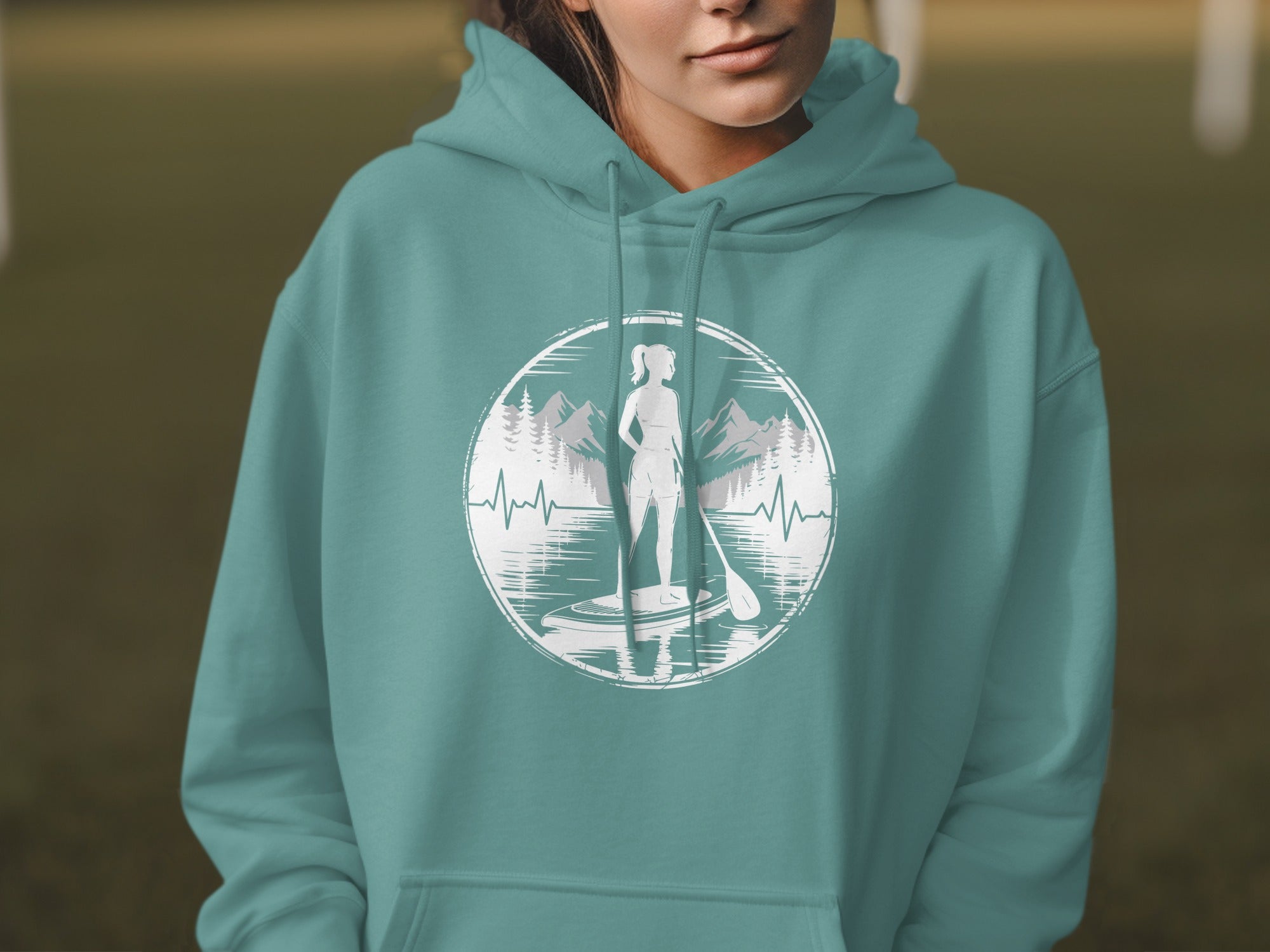 Woman wearing teal hoodie with paddleboarding graphic.