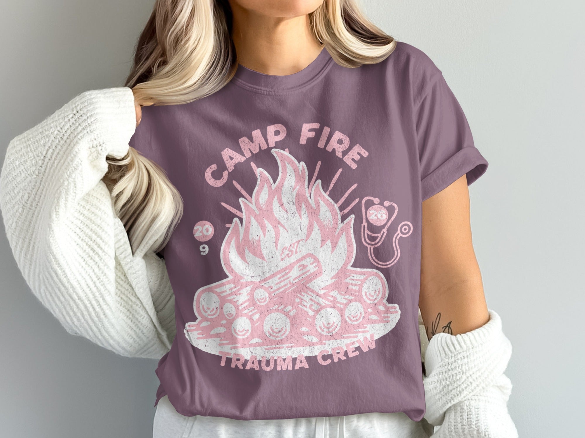 Purple t-shirt with a pink campfire graphic and "Camp Fire Trauma Crew" text.