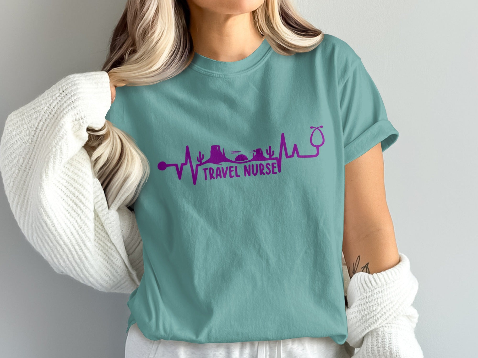 Teal t-shirt with purple "Travel Nurse" text and electrocardiogram motif.