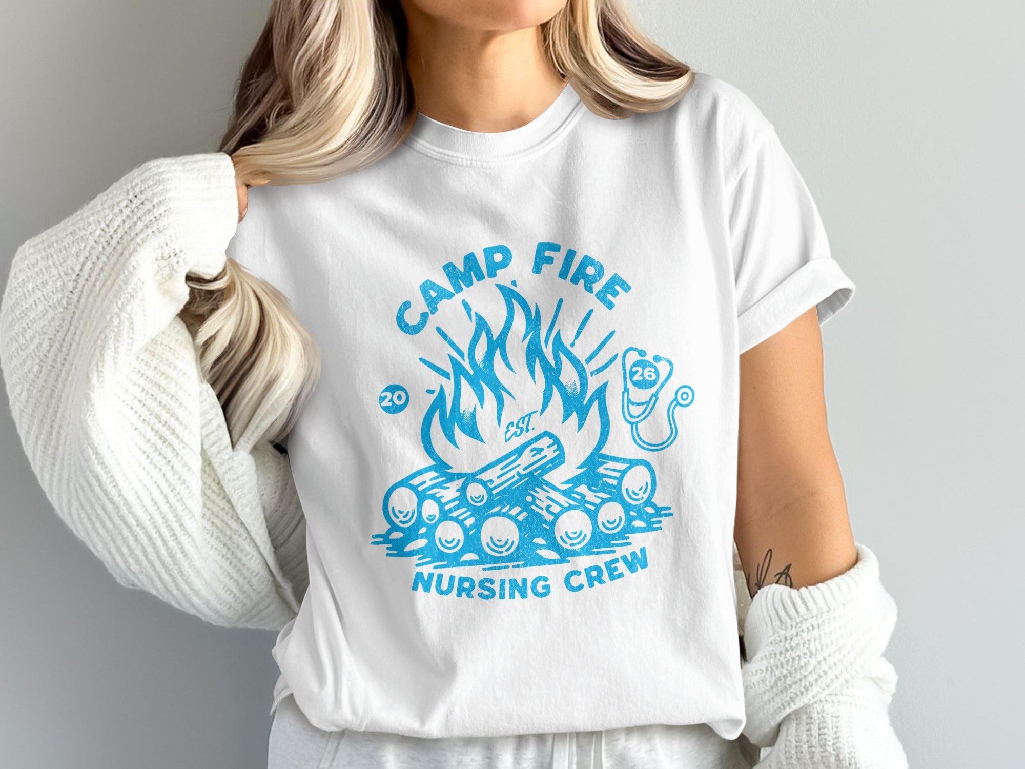 White t-shirt with blue "Camp Fire Nursing Crew" graphic featuring campfire and stethoscope.