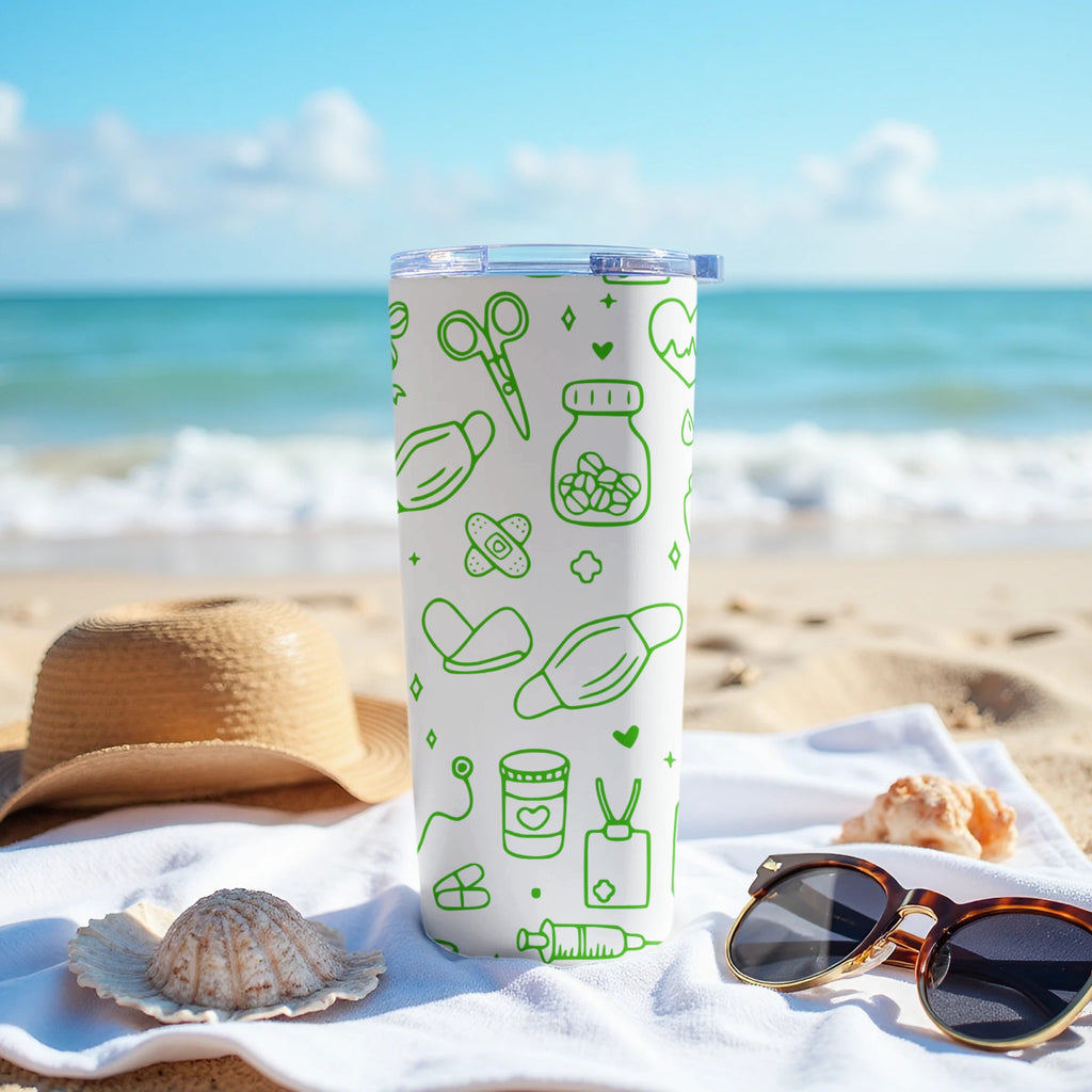 Green medical icons on a white insulated tumbler on a beach towel.