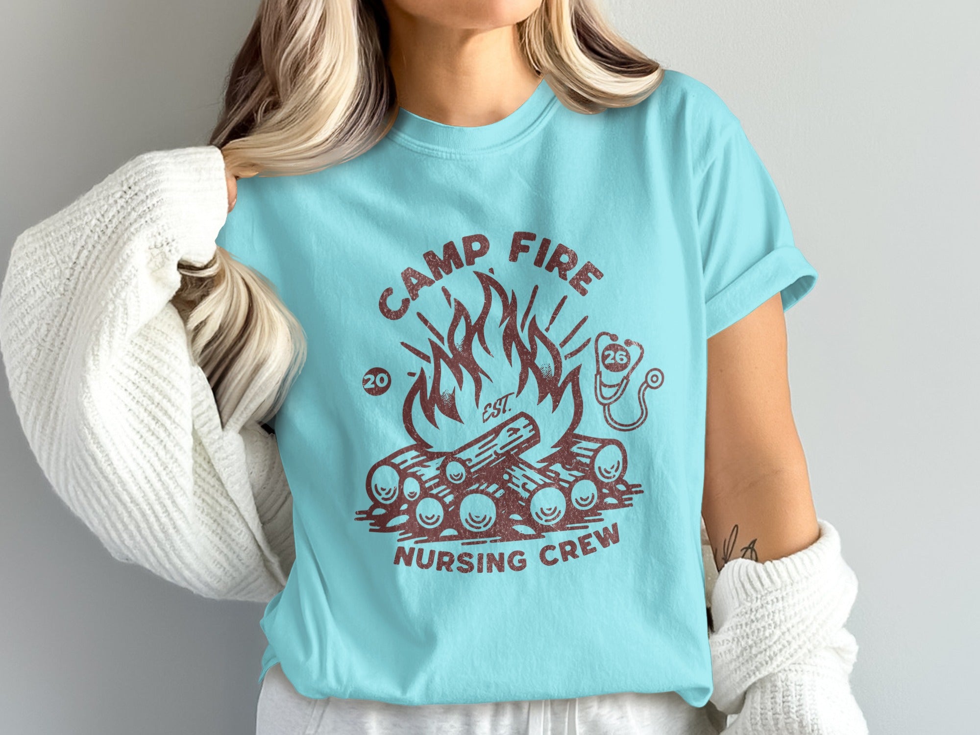 Teal t-shirt with distressed campfire graphic and "Camp Fire Nursing Crew" text.
