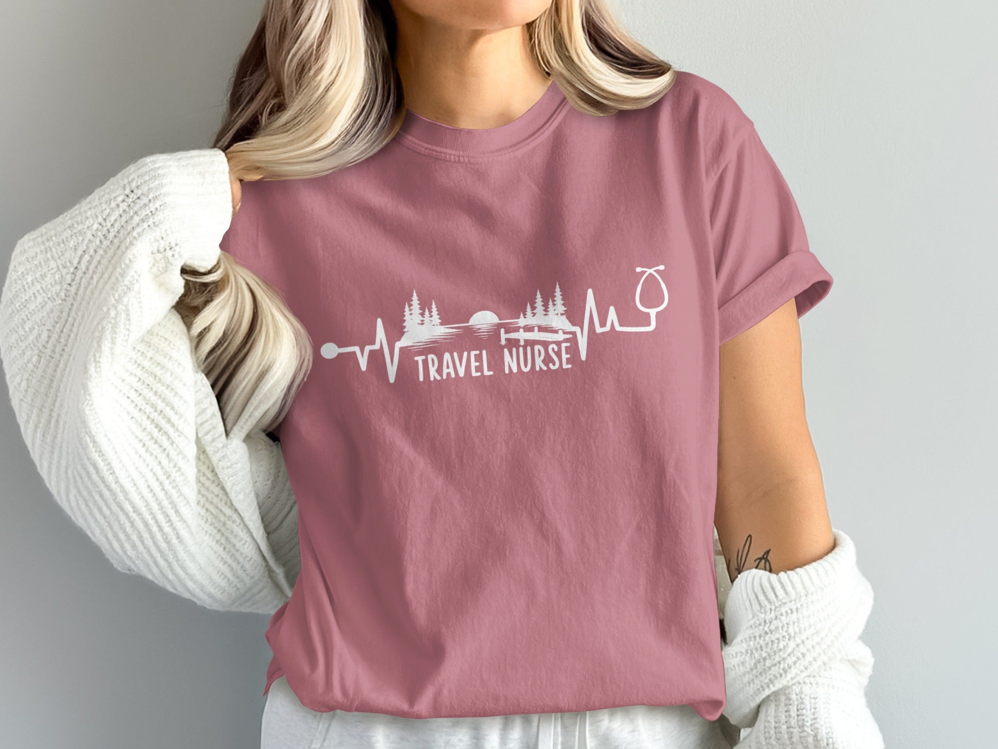 Pink t-shirt with "Travel Nurse" text and a heartbeat graphic of trees and a lake.