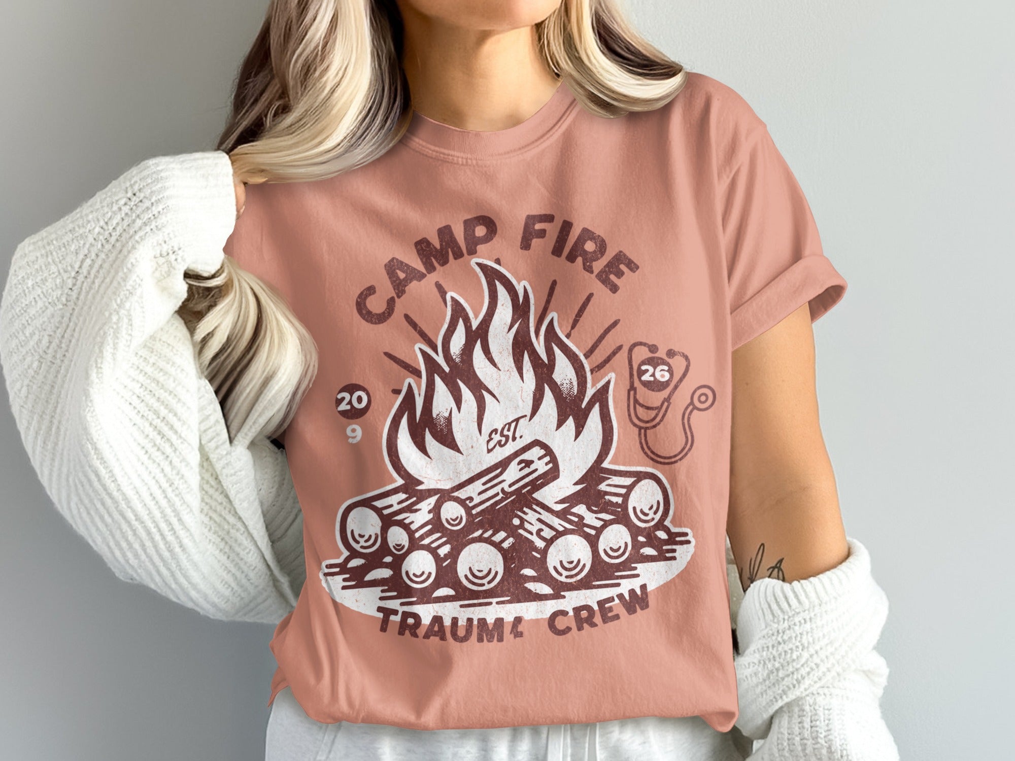 Pink t-shirt with campfire graphic and "Camp Fire Trauma Crew" text.
