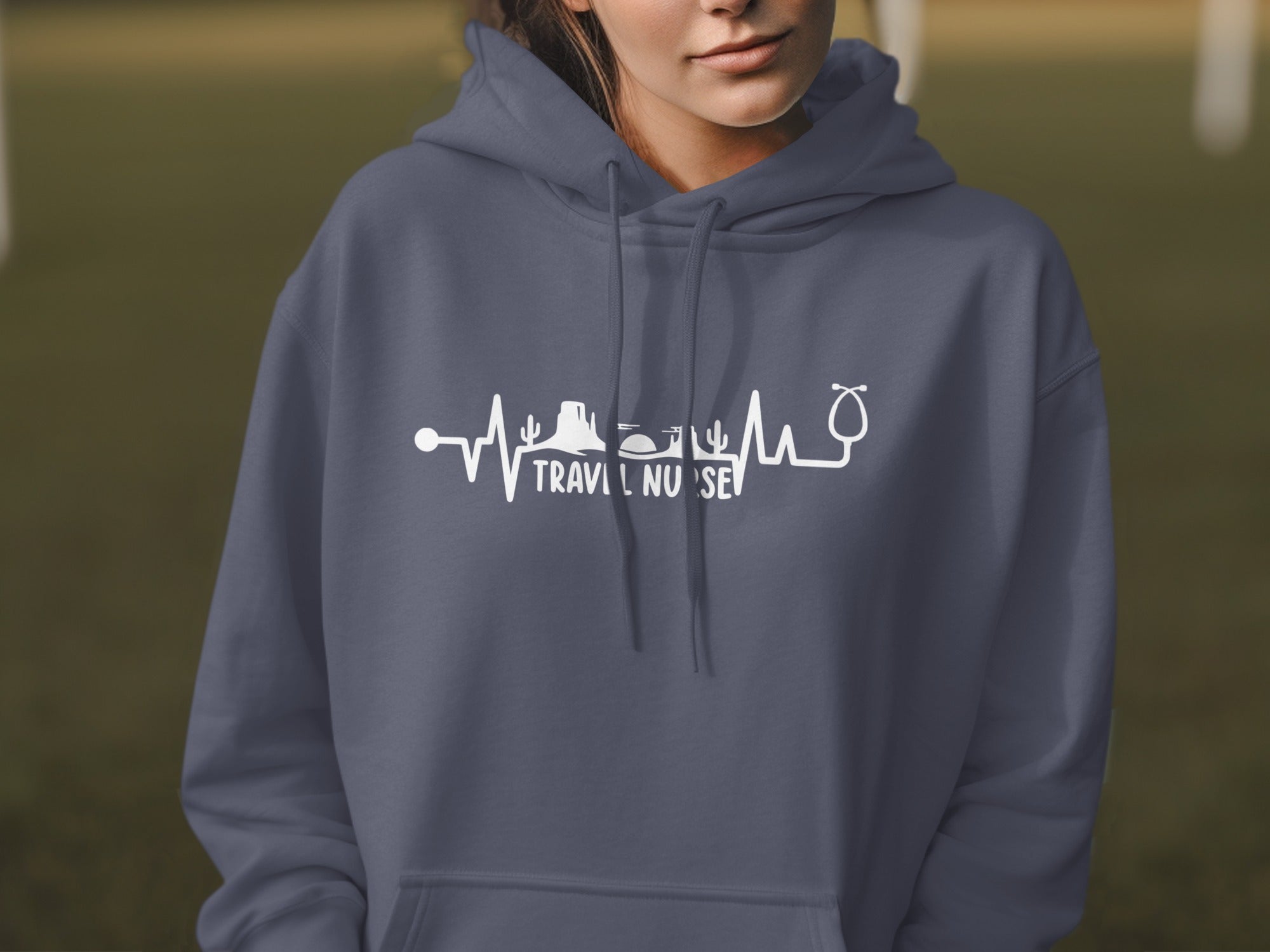 Gray hoodie with a white heartbeat line featuring desert landscape and stethoscope, and "TRAVEL NURSE".