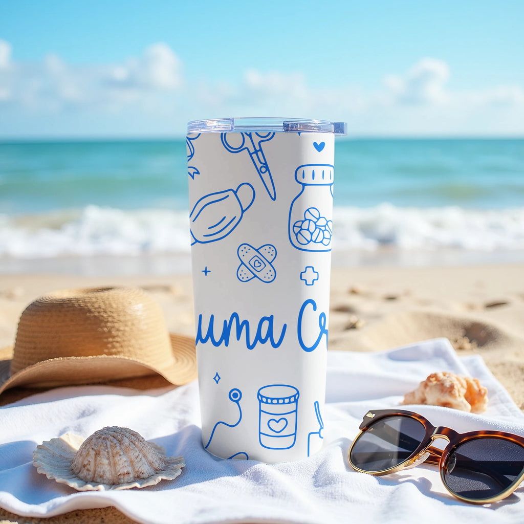 White tumbler with blue medical icons on a beach towel, next to sunglasses and a hat.