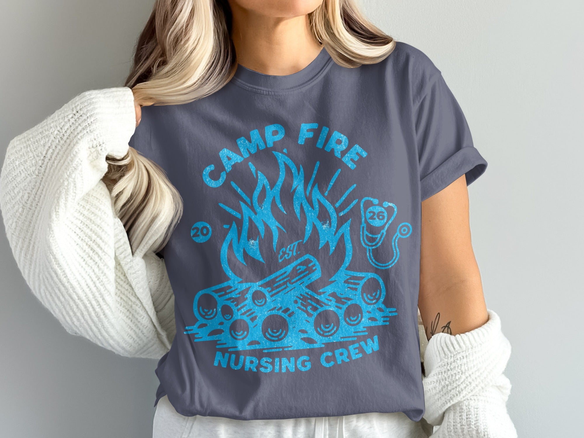 Camp Fire Nursing Crew text on a charcoal grey t-shirt with a blue graphic of a campfire.