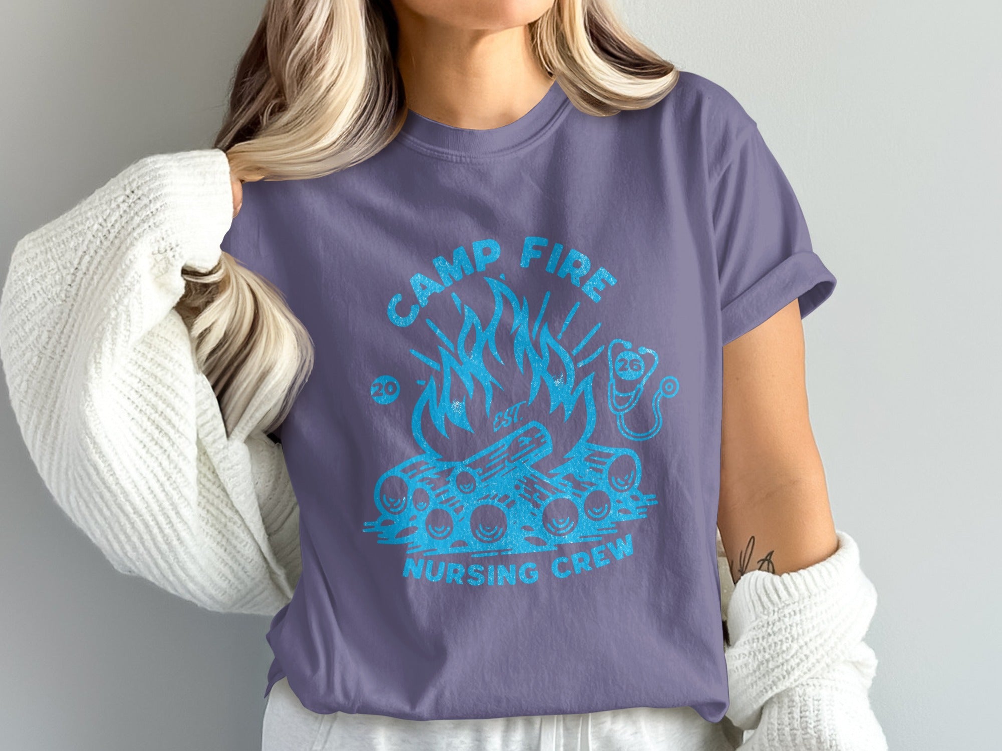Purple t-shirt with blue graphic of campfire and "Camp Fire Nursing Crew" text.