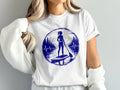 Woman on paddleboard with mountains and lake graphic on white t-shirt.