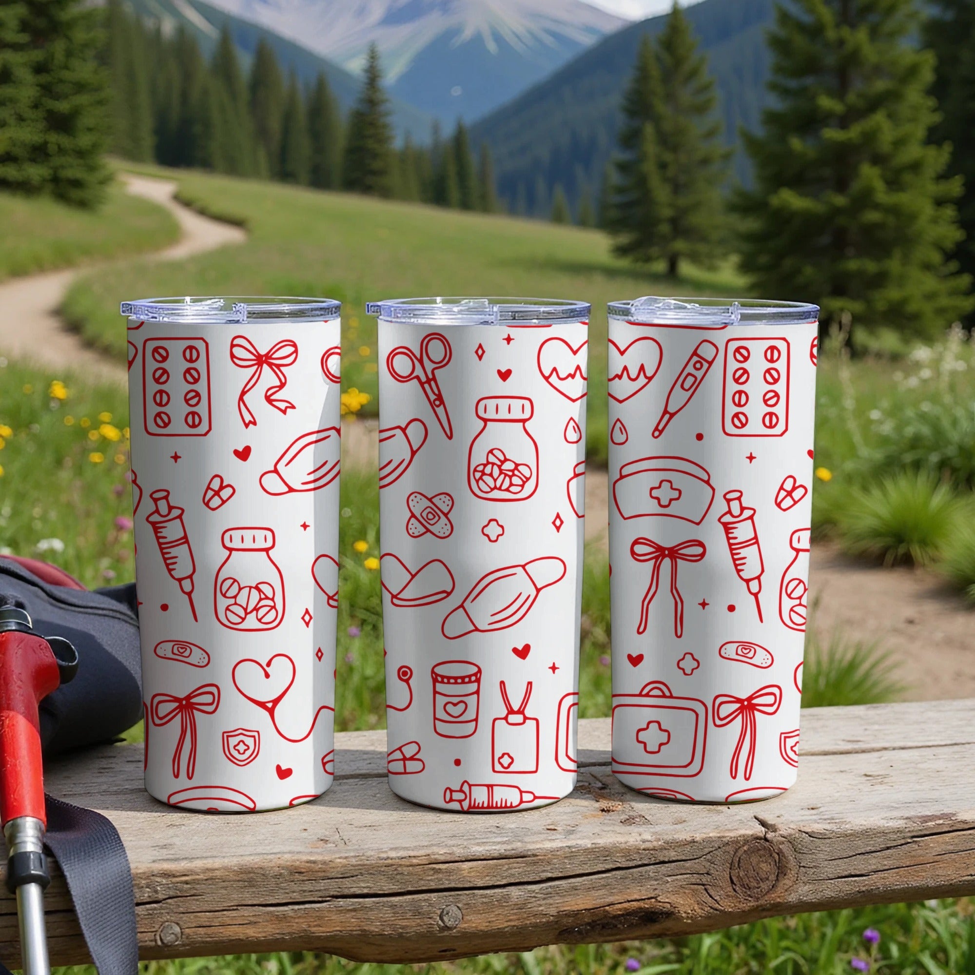 Three white tumblers with red medical icons and lids, on a wooden surface.