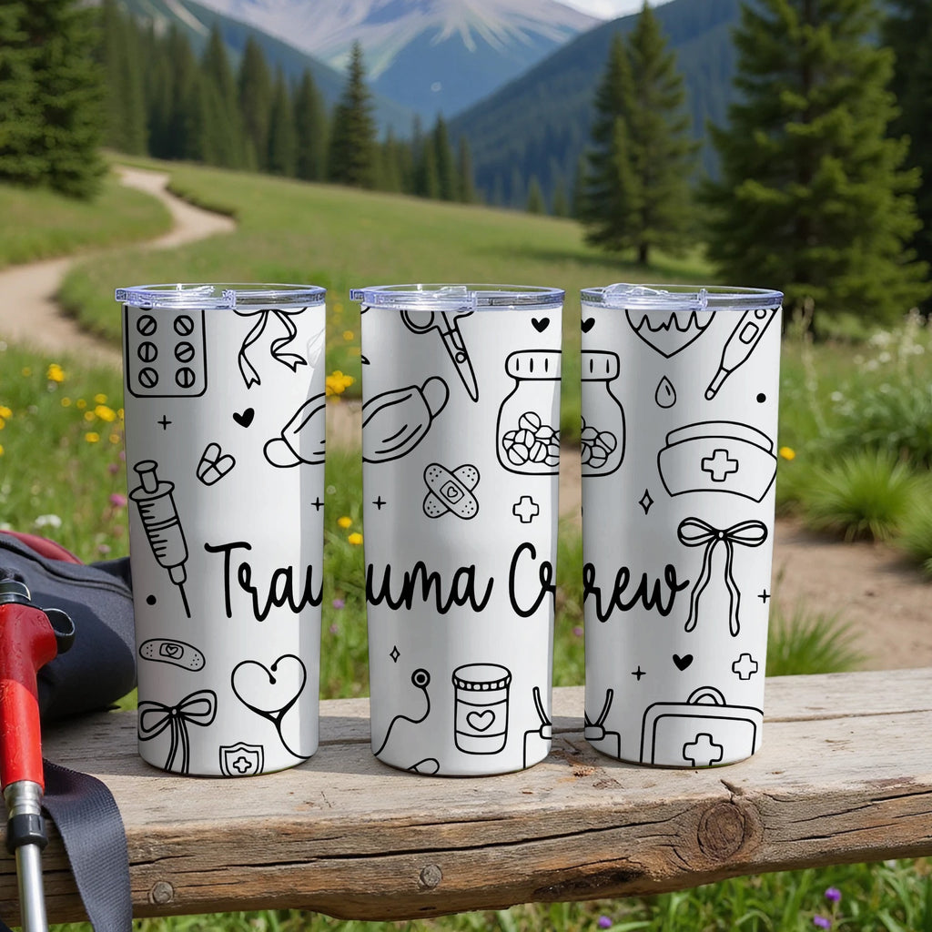 Three white tumblers with medical icons and "Trauma Crew" text on a wooden surface.