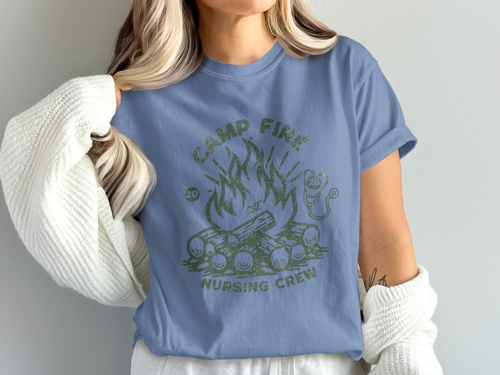 Blue t-shirt with green campfire graphic and "CAMP FIRE NURSING CREW" text.