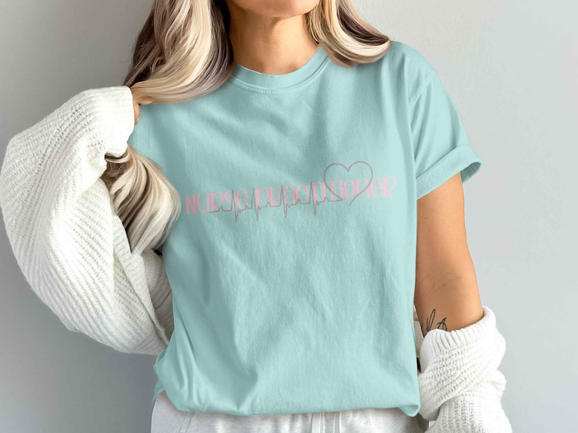 Light blue t-shirt with pink text "Nurse Practitioner" and a heart monitor line.