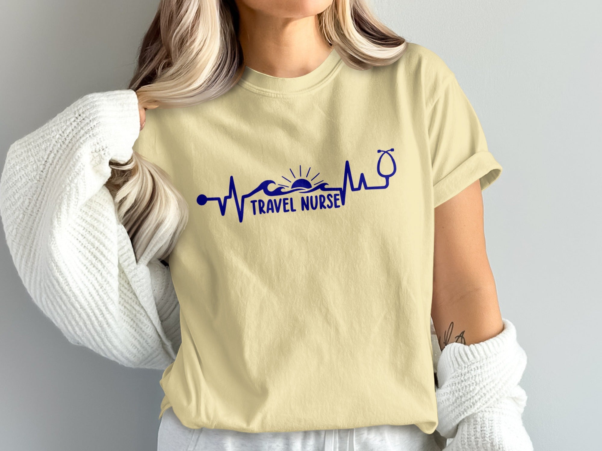 Beige t-shirt with navy blue "Travel Nurse" text and stethoscope heartbeat graphic.